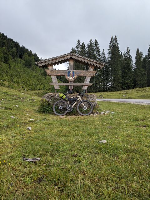 My Cannondale Topstone leaning against the summit sign on Postalm.