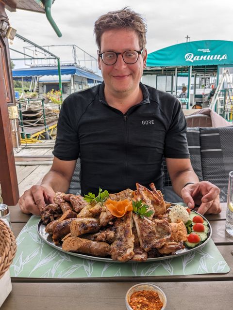 Paul staring at a huge plate filled with grilled meat and sausages.