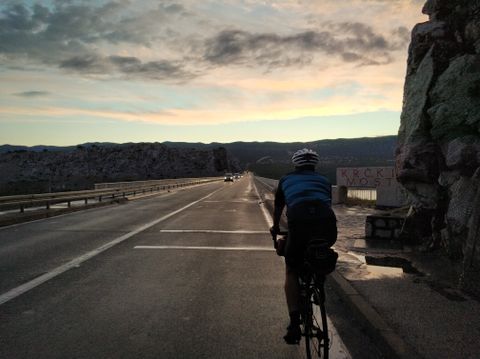 Photo of Paul riding into the dawn on the Krk bridge